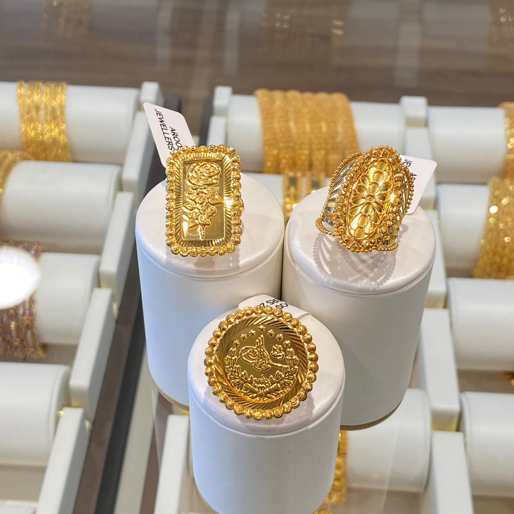 Patterned 22 carat gold rings on black, one upright and in focus