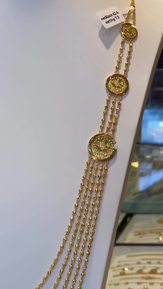 A five-strand 21 carat gold necklace and matching earrings on a white bust in the cabinet